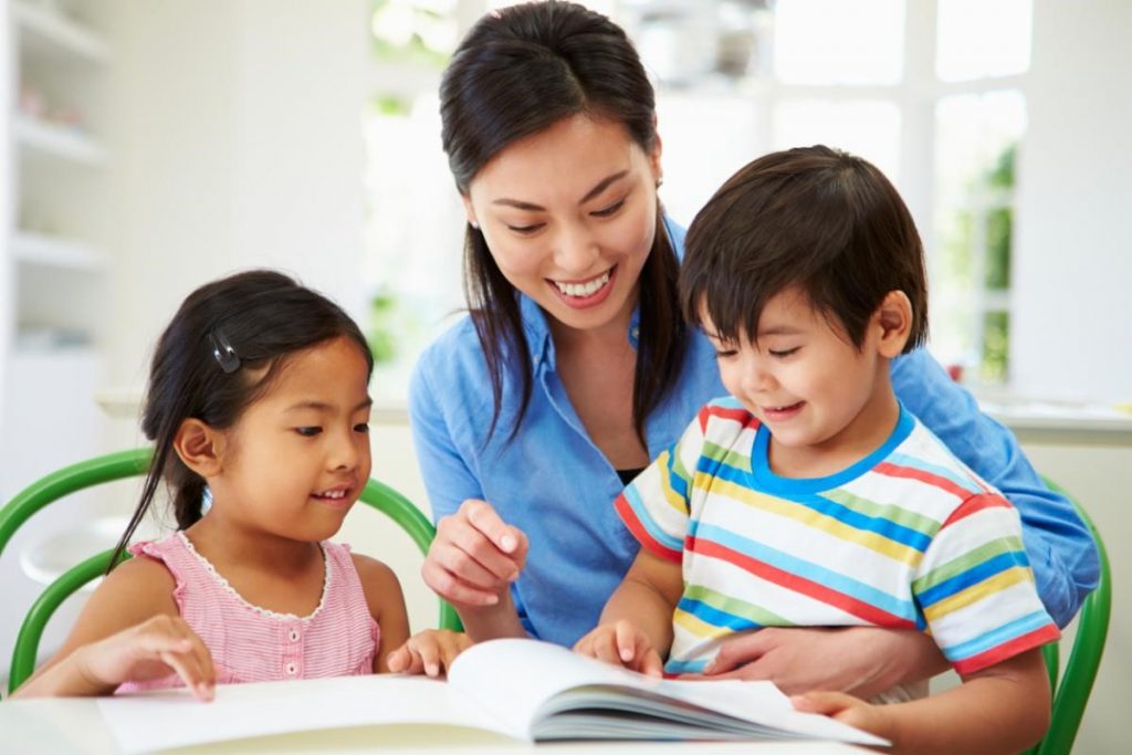 A volunteer mentor reading with two young students